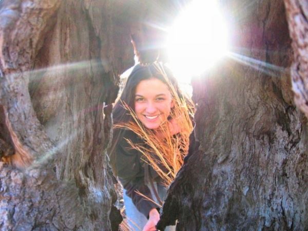Woman Smiling from Behind Rocks